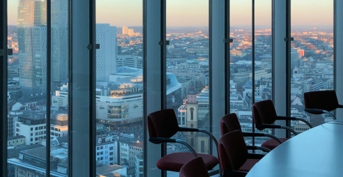 A boardroom with large glass windows and a dusky view of a city.