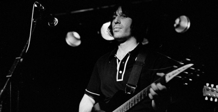 A black and white shot of Tony Barker playing the guitar.