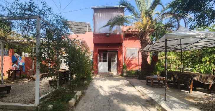 The terracotta exterior of the Sikka community centre, with a beautiful patio and trees.