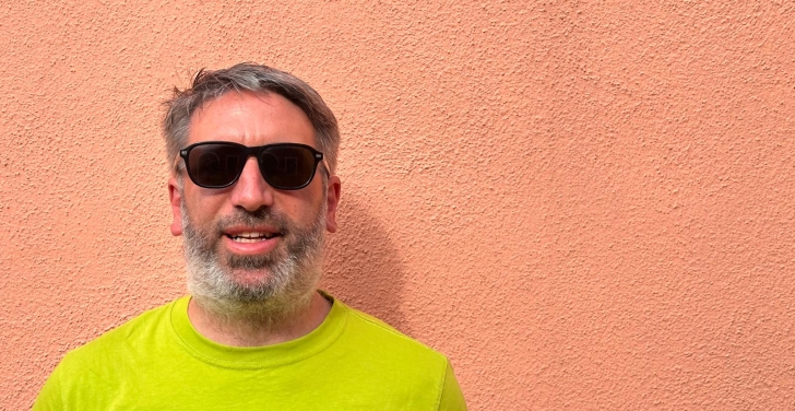 Photo of Tony Barker wearing sunglasses and a lime T-shirt against the backdrop of a peach-coloured wall.