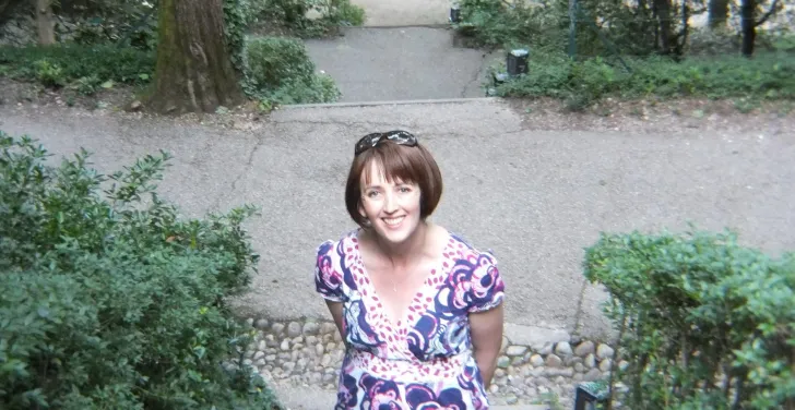 Claire O'Brien pauses for a photo on steps surrounded by trees in Lyon.