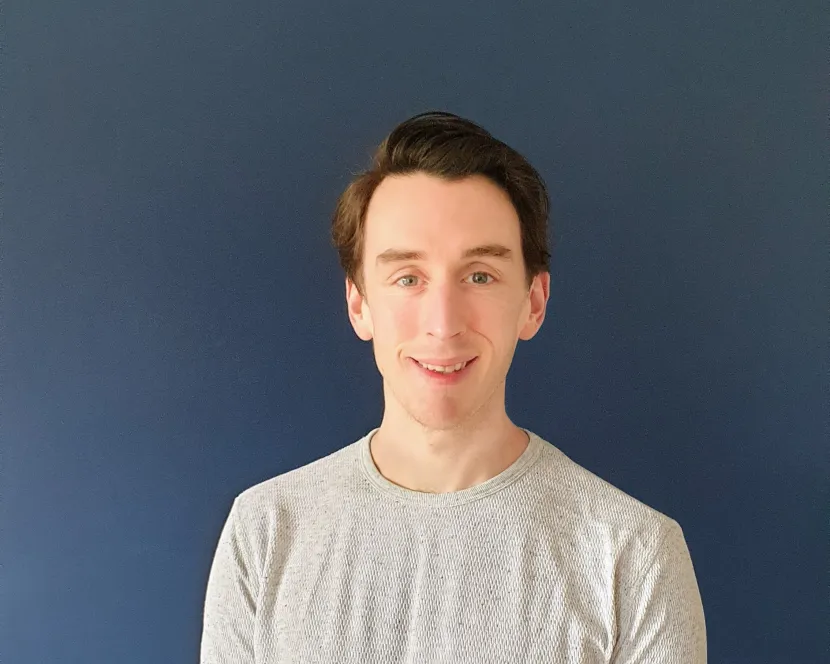 Gavin Hughes stands against a dark blue background.