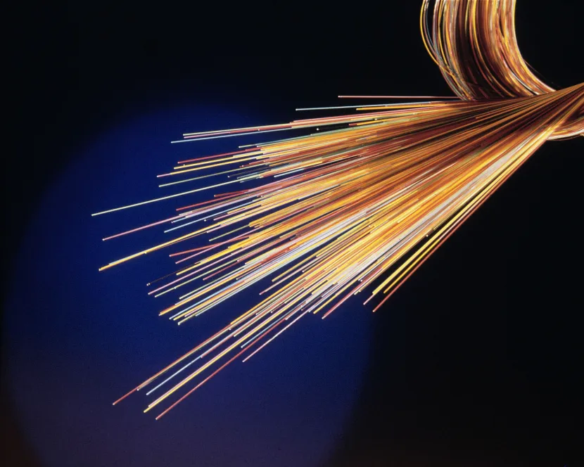 A section of fibre optic cable is foreground against a dark background